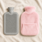Bouillotte à eau gris clair et housse rose poudré posées sur un plaid beige