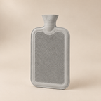 Bouillotte à eau gris clair à surface striée, vue de trois quarts sur fond beige