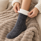 Mains remontant une chaussette pilou-pilou gris foncé sur un plaid en maille
