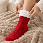 Mains remontant une chaussette pilou-pilou rouge sur un plaid en maille