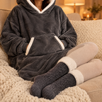 Mains dans la grande poche du sweat plaid gris foncé, chaussettes pilou-pilou grises aux pieds