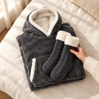 Sweat plaid gris foncé plié et chaussettes pilou-pilou grises posés sur un lit